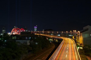 Brücke mit Leuchtspuren von Autos zum Festland von einer künstlichen Insel in Kobe.