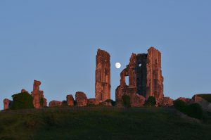 Der Mond zwischen den Ruinen von Corfe Castle im Licht des späteren Abends.